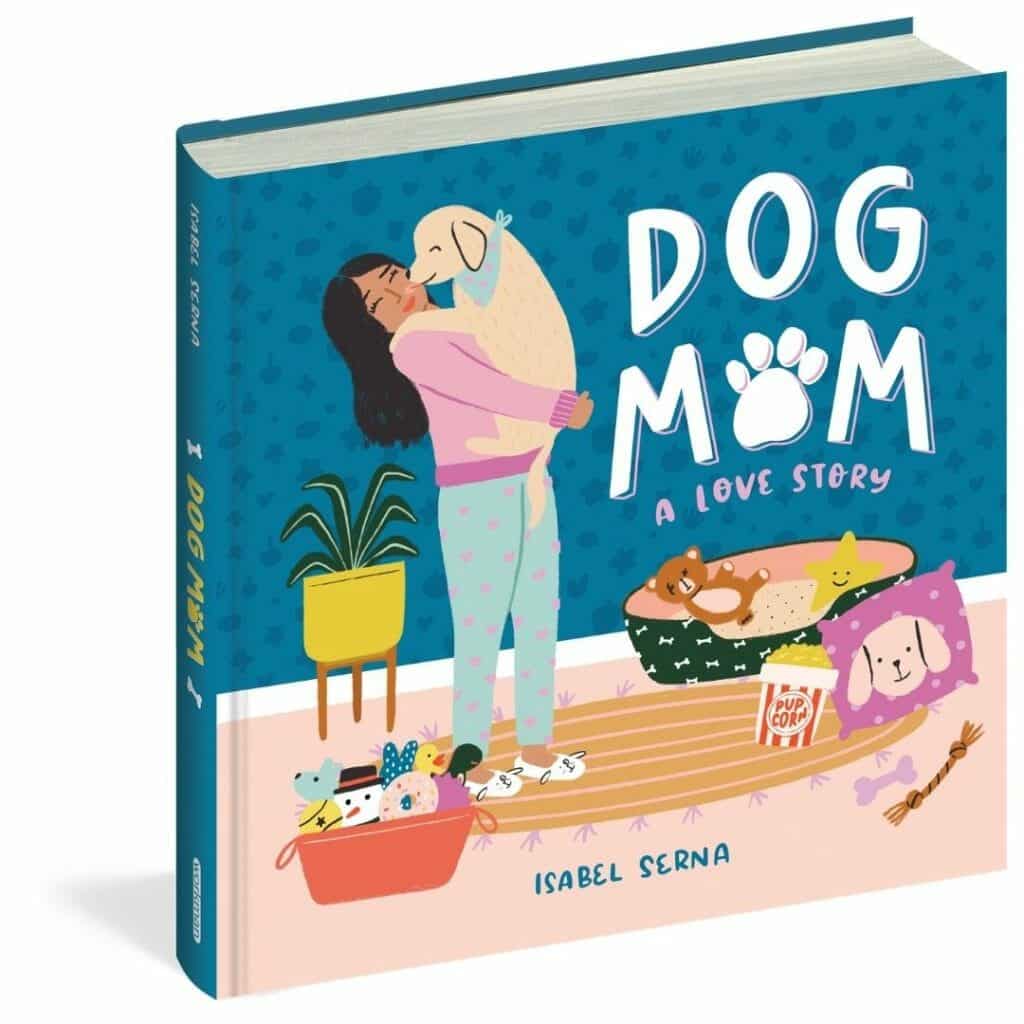 The cover of Dog Mom features a woman holding her puppy surrounded by dog gear like toys, a bed, and decor. 