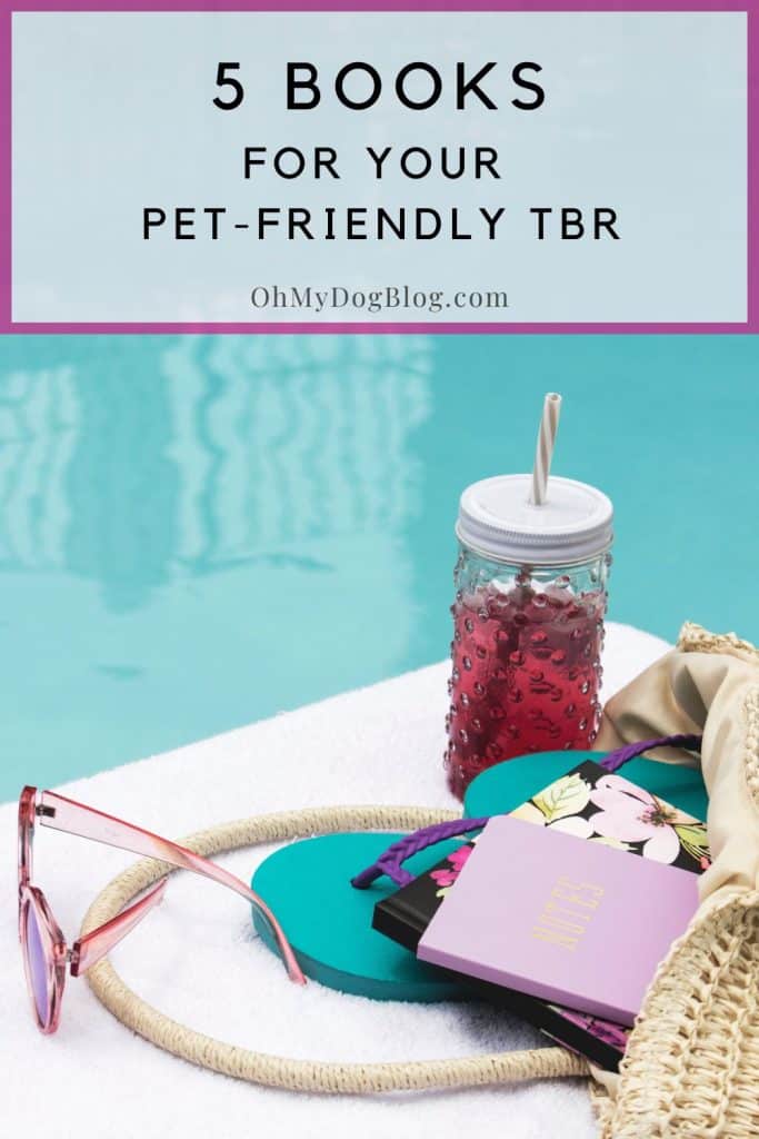 At the edge of a pool, on top of a white beach towel sits an iced tea drink in a glass container with a striped straw. Behind the beverage is a straw pool bag tipped over and the contents spill out onto the towel, including a pair of pink sunglasses, teal and purple flip flops, a hardback book with a floral cover, and a pink notebook with Notes written in gold on the cover. The text overlay reads: 5 books for your pet-friendly TBR