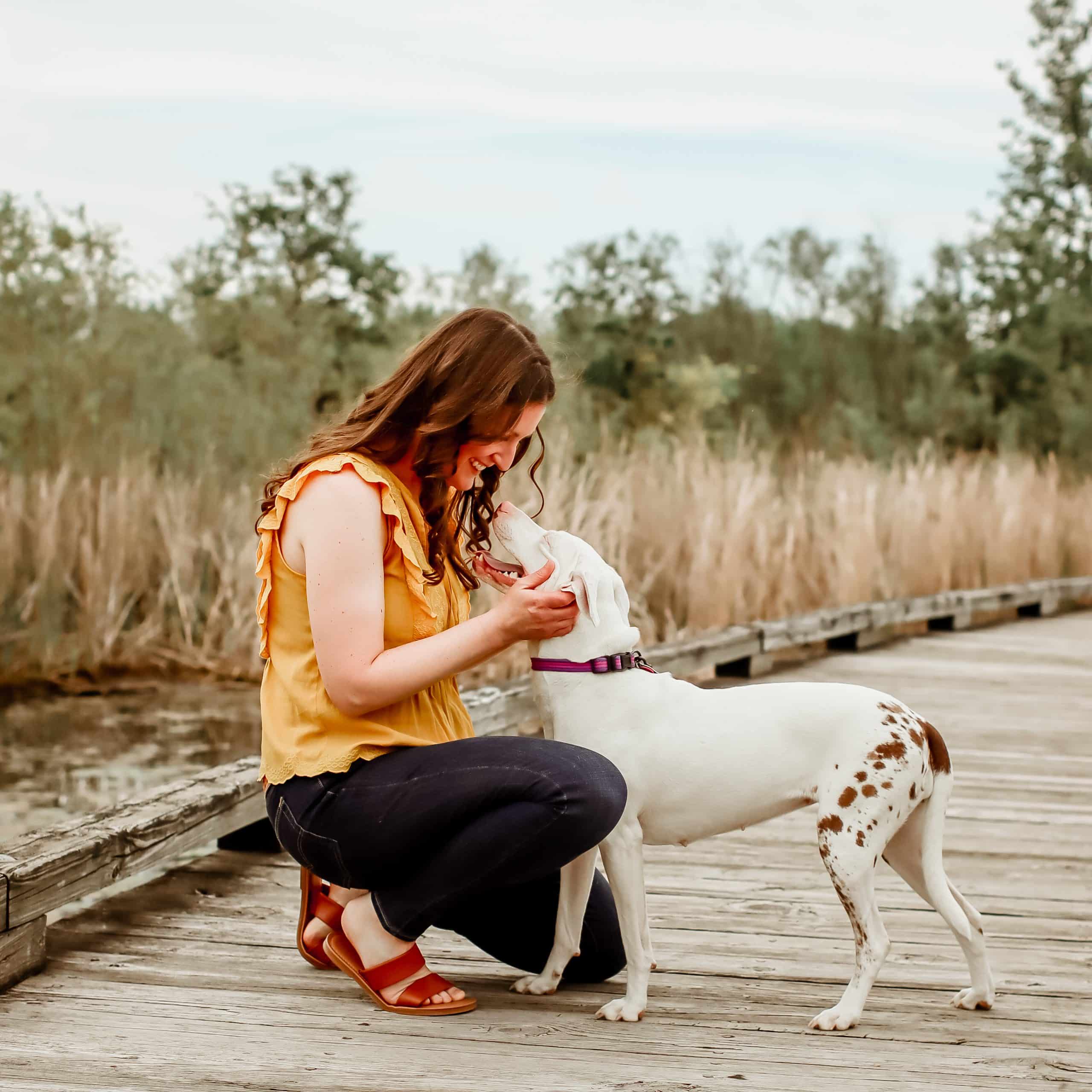 Me wearing a yellow blouse and blue jeans, and Penny, photographed on a wooden bridge spanning a wetland